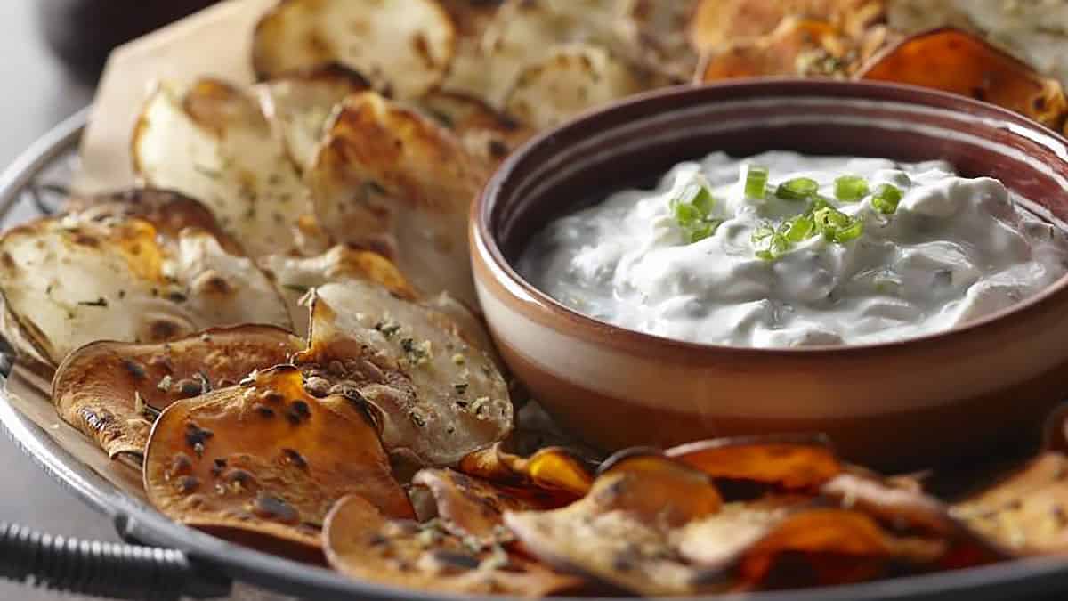 Savory grilled mushrooms with creamy dip garnished with green onions, served on a rustic platter for healthy, flavorful snacks or appetizers.